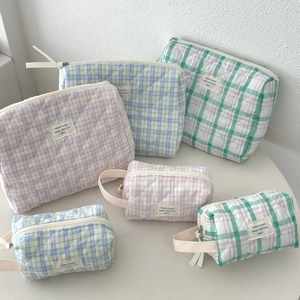 Detailed view of quilted grid cosmetic bags in pastel colors on a white minimalist background