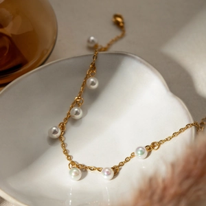 Detail of 18K gold stainless steel chain anklet with white pearls in a ceramic dish