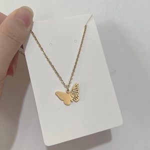 Vue détaillée du pendentif papillon avec design givré et ajouré sur une chaîne dorée