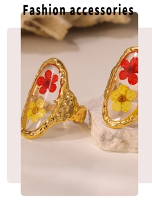 Detailed shot of golden enamel rings with embedded red and yellow dried flowers in resin