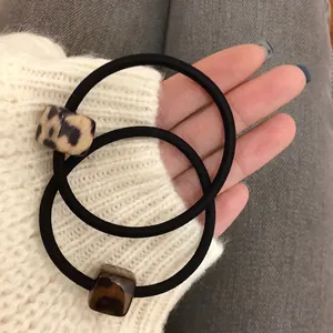 Hand holding leopard print and tortoiseshell square beads hair ties with elastic bands