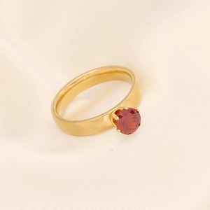 Bague classique en acier inoxydable doré avec une pierre rouge sur fond de soie