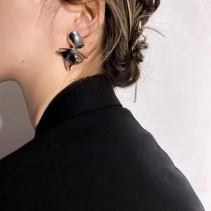 Vue latérale de boucles d'oreilles argentées torsadées portées par un mannequin chic