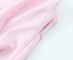Close-up of light pink top featuring high-quality invisible zipper and woven fabric detail