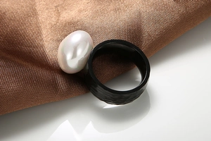 Macro shot of hammered black textured ring paired with a natural white baroque pearl