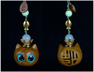 Front and back detail of a wooden cat pendant with blue eyes and hollowed Fu character