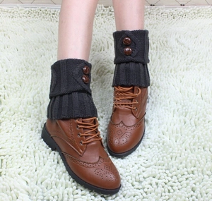 Close-up of dark grey knitted leg warmers with brown vintage buttons on leather boots