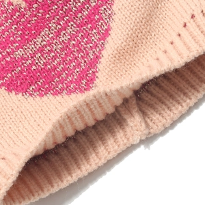 Detail of ribbed knit cuff on beige winter hat with pink heart jacquard pattern