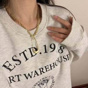 Close-up of gold plated Cuban link necklace with pin pendant on model neck