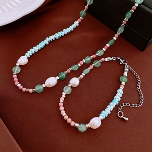 Détail du collier et bracelet en perles avec pierres vertes sur un tissu en soie brune