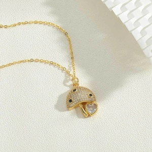 Detailed close-up of a golden mushroom pendant with white pavé zircons and a heart charm