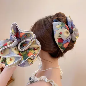 Floral chiffon scrunchie and bow hair clip set shown on a woman back hairstyle