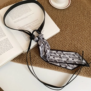 Detail of paisley silk scarf tassel belt with black leather cord on a vintage book