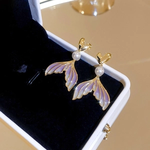Detailed view of pearl mermaid tail earrings with purple gradient finish in a box