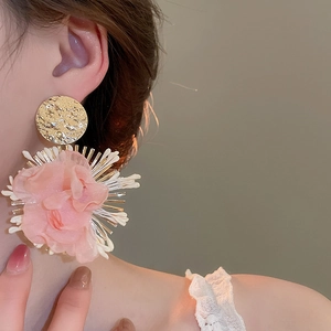 Detailed shot of pink chiffon flower earrings with golden metal studs and textured petals