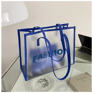Detail of blue frosted transparent tote bag with fashion lettering on a desk setting
