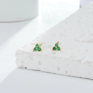 Macro view of dainty gold-plated S925 silver stud earrings with three green zircons