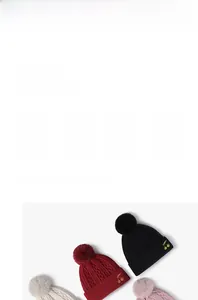 Detailed embroidery of golden cherry patterns on a warm winter knit pom-pom hat