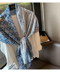 Detail view of blue and white scarf featuring geometric patterns and fringe tassels