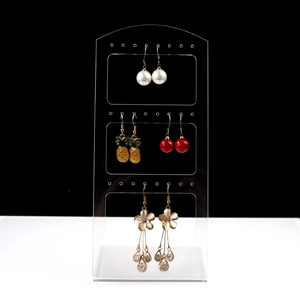 Three-tier clear acrylic earring stand displaying pearl, pineapple, and floral tassel earrings