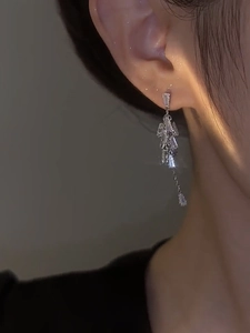 Close-up of elegant silver tassel earrings with sparkling zircon stones on a model