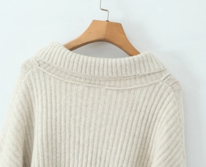 Makroaufnahme von cremefarbenem Strickpullover-Kragen und vertikaler Rippenstruktur