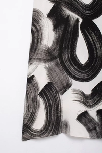 Close-up of lightweight fabric with black brushstroke print on off-white elegant dress