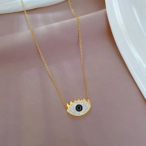 Detail of gold evil eye pendant with blue gem on pink silk background