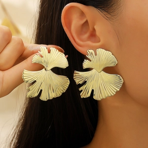 Chic oversized golden ginkgo leaf earrings with realistic vein texture on female model