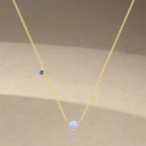 Detail of gold necklace with round opal center and blue and white diamond accents