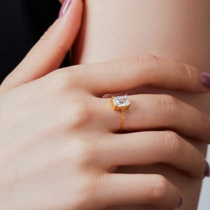 Detailed view of adjustable gold chain ring featuring a square clear zircon on model's finger