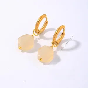 Detail view of gold hoop earrings with hexagonal beige natural stone pendant