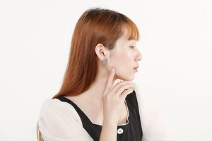 Close-up of a female model wearing silver vintage hollow earrings with floral engraving