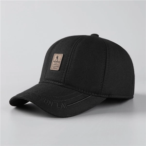 Detail of winter baseball cap for men featuring black fabric and brown leather logo patch