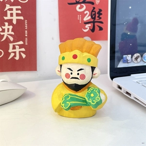 Macro detail of hand-painted Caishen figure with green Ruyi scepter and yellow finish