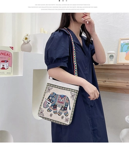 Detailed embroidery of elephant motif on ethnic style canvas crossbody bag with woven strap