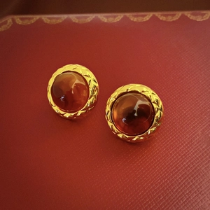 Macro shot of gold quilted metal border with amber resin center on red texture