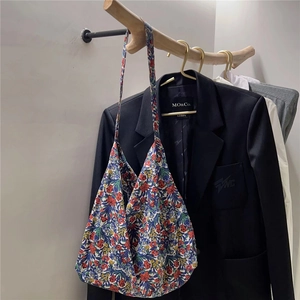 Close-up of vintage floral print cotton tote bag hanging on a wooden hanger with clothing