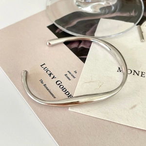 Artistic detail of minimalist 925 sterling silver open bangle on a stylish magazine background