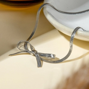 Detailed close-up of a silver bow-shaped snake chain necklace in minimalist metal style