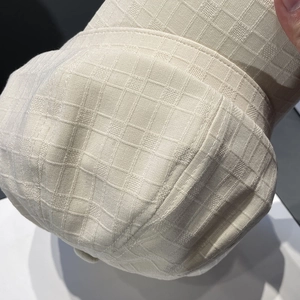 Close-up of the cream checkered jacquard fabric and stitching of the baker boy hat