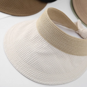 Détails du pare-soleil beige montrant la texture en paille tressée et le nœud élégant