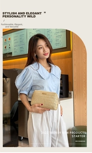 Detail of woven beige crossbody bag with metal accent worn by a model in a cafe