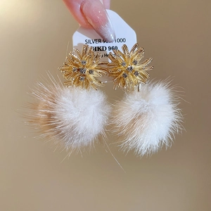 Close-up of Silver 925 earrings with gold firework zircon studs and white fur balls