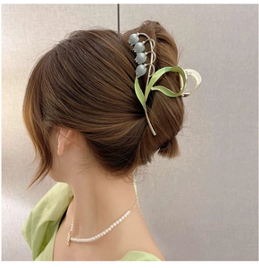 Close-up of Lily of the Valley hair claw clip with green leaves and blue petals on hair