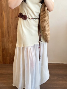 Detail of a floral waist chain with wood beads and ribbons on a beige knit dress