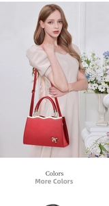 Detail of red bridal handbag with a gold bow accent worn by a model in a light dress