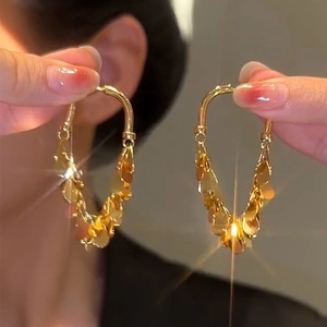 Macro shot of gold-plated U-shaped earrings with cascading metallic fringe tassels