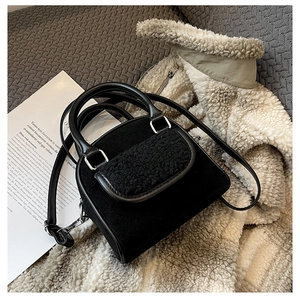 Detail of black plush faux fur and matte handbag with adjustable strap in casual setting