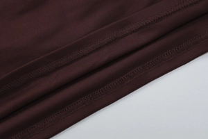 Macro shot of precise overlock stitching detail on brown knit dress fabric surface